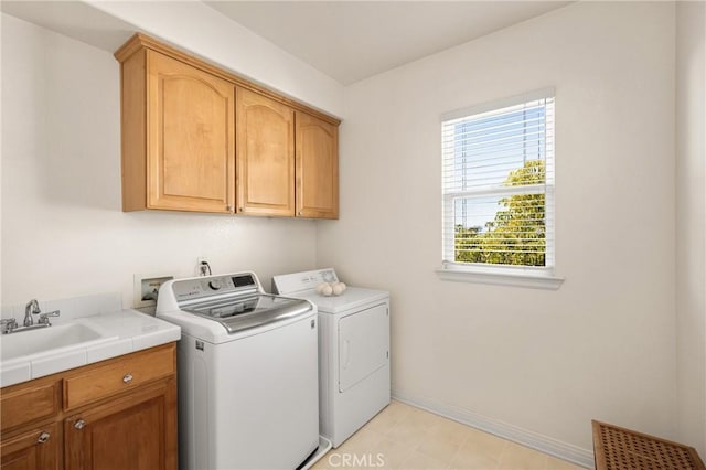 clothes washing area featuring a sink, baseboards, cabinet space, and independent washer and dryer