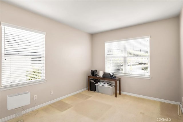 office space featuring a wealth of natural light, baseboards, and light colored carpet