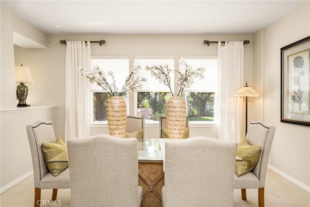 carpeted dining space featuring baseboards