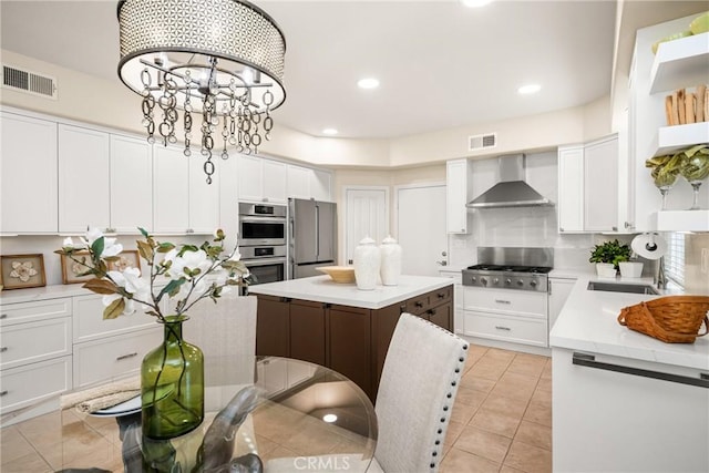 kitchen featuring visible vents, a notable chandelier, appliances with stainless steel finishes, and wall chimney range hood