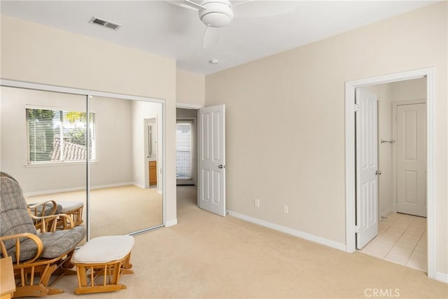 living area featuring visible vents, light carpet, baseboards, and ceiling fan