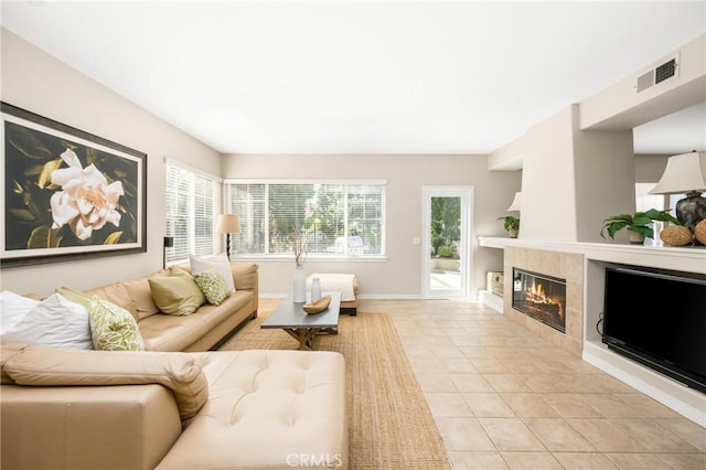 living room featuring visible vents, baseboards, light tile patterned flooring, and a tile fireplace