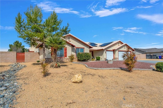 ranch-style home with fence, a garage, roof mounted solar panels, and stucco siding