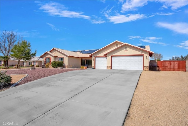 view of front facade featuring fence, driveway, solar panels, an attached garage, and stucco siding