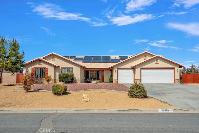 single story home featuring a tile roof, roof mounted solar panels, fence, concrete driveway, and an attached garage