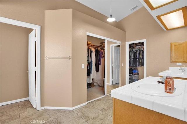 full bath featuring vanity, baseboards, visible vents, a spacious closet, and tile patterned floors