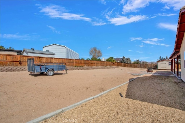 view of yard featuring an outdoor structure, a fenced backyard, and a shed