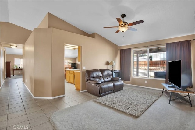 living room featuring light tile patterned flooring, baseboards, a ceiling fan, and vaulted ceiling