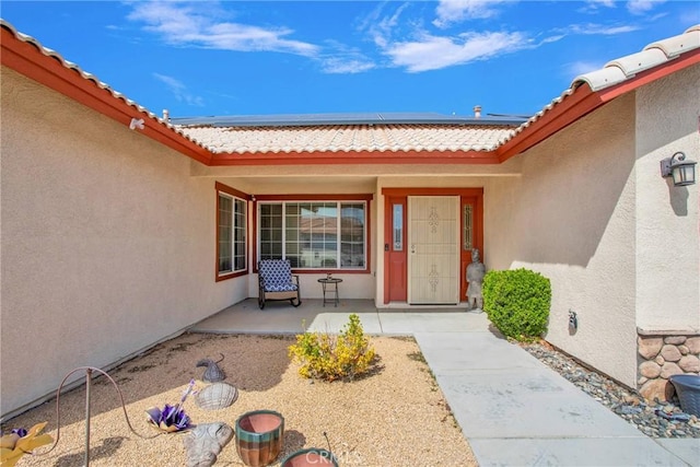 20368 Majestic Dr, Apple Valley, CA 92308 - view of exterior entry with roof mounted solar panels, stucco siding, a tiled roof, and a porch