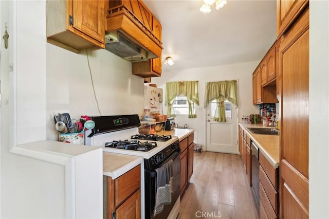 kitchen featuring gas stove, a sink, light countertops, dishwasher, and brown cabinets