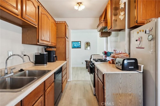 kitchen featuring a sink, freestanding refrigerator, range with gas cooktop, light countertops, and dishwasher