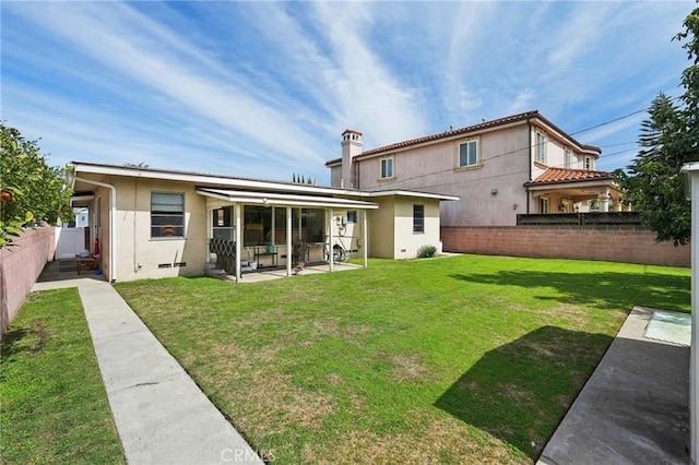 back of house featuring a yard, stucco siding, a patio, and a fenced backyard