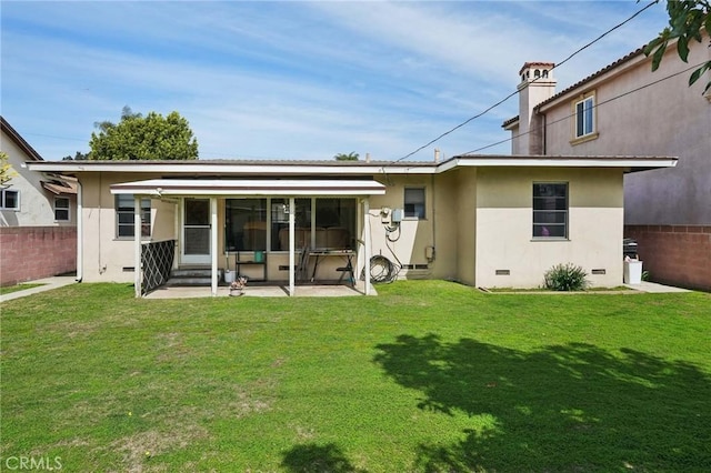 back of property with stucco siding, a lawn, fence, and crawl space