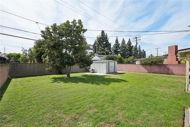 view of yard featuring an outbuilding, a fenced backyard, and a storage shed