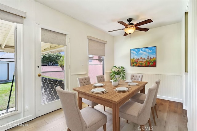 dining area featuring hardwood / wood-style flooring, plenty of natural light, a ceiling fan, and a wainscoted wall