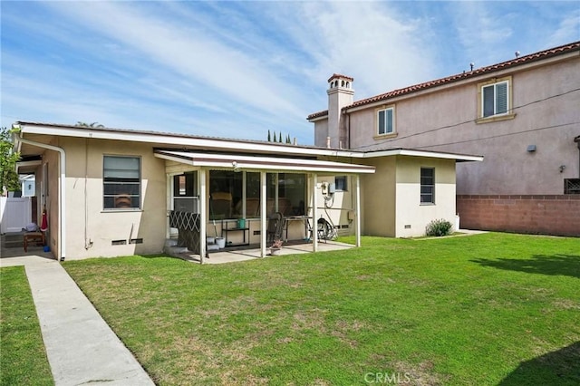 back of property with a patio area, stucco siding, a lawn, a chimney, and crawl space