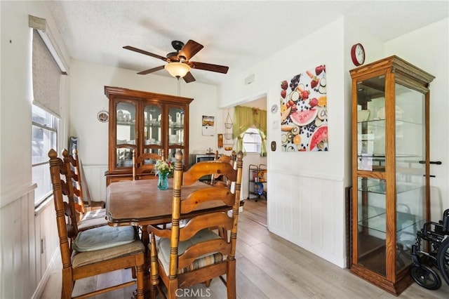 dining space featuring wainscoting, a textured ceiling, ceiling fan, and wood finished floors