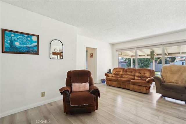 living room featuring baseboards, a textured ceiling, and light wood-style floors