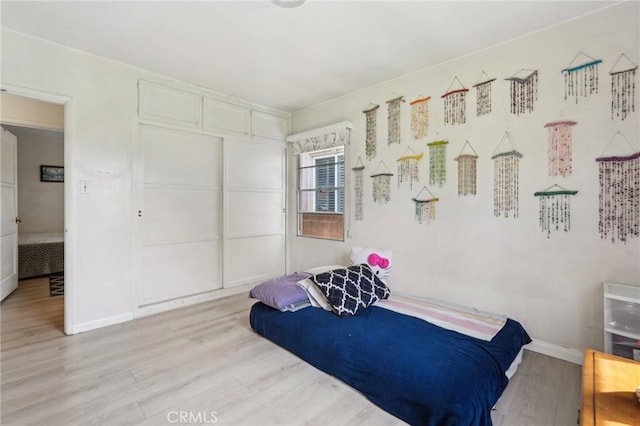 bedroom featuring light wood finished floors and baseboards