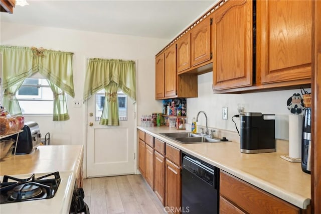 kitchen with brown cabinets, light countertops, black dishwasher, and a sink