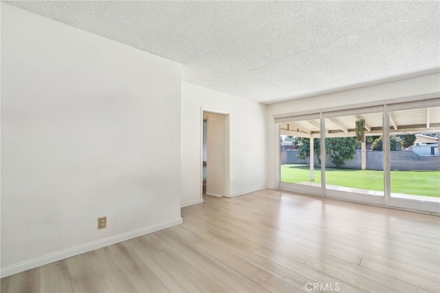 unfurnished room featuring baseboards, a textured ceiling, and light wood finished floors