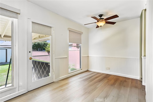 spare room with ceiling fan, a healthy amount of sunlight, hardwood / wood-style floors, and wainscoting