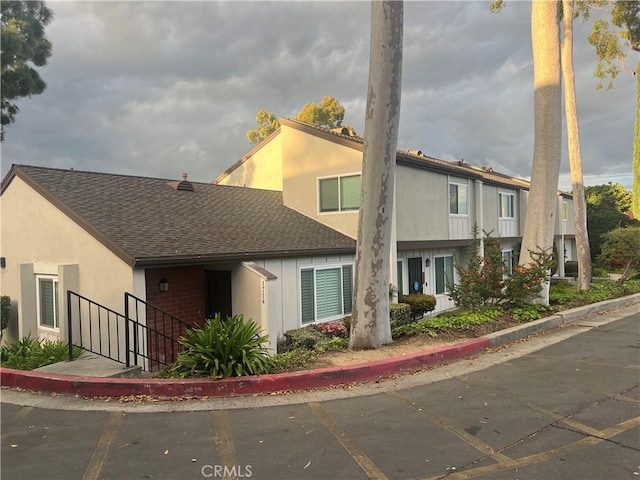 view of front of property with a shingled roof and stucco siding