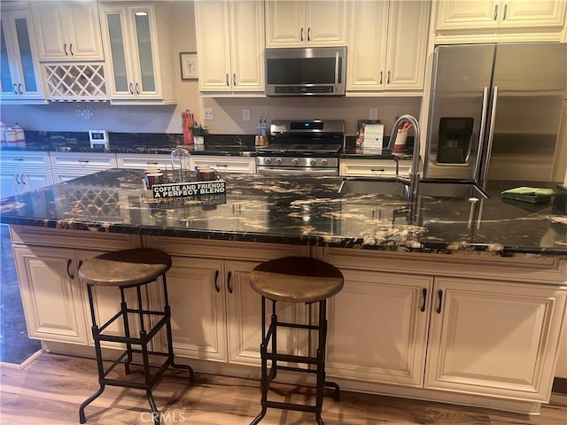 kitchen with a breakfast bar, white cabinetry, stainless steel appliances, and glass insert cabinets