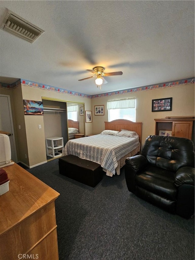 carpeted bedroom with visible vents, a textured ceiling, and a ceiling fan