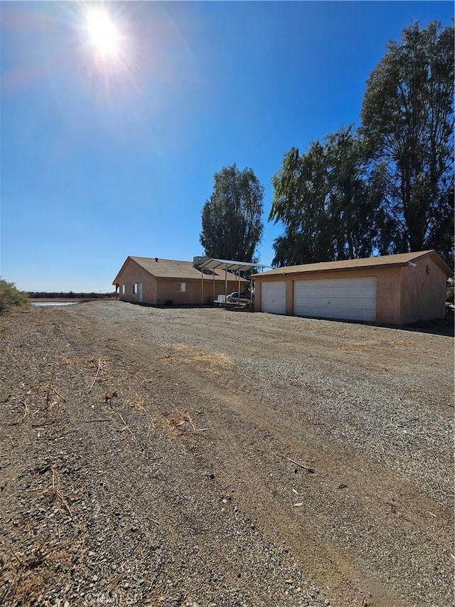 view of yard with a detached garage, an outdoor structure, a carport, and driveway