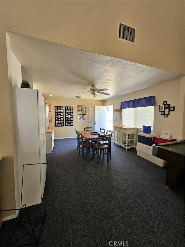dining room featuring a textured ceiling, visible vents, ceiling fan, and dark colored carpet