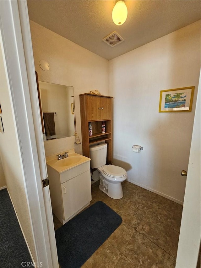 bathroom featuring visible vents, baseboards, toilet, vanity, and a textured ceiling