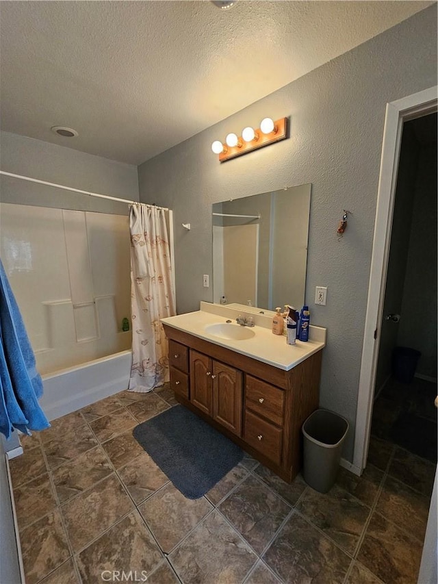 full bathroom featuring a textured ceiling, shower / tub combo with curtain, vanity, and a textured wall