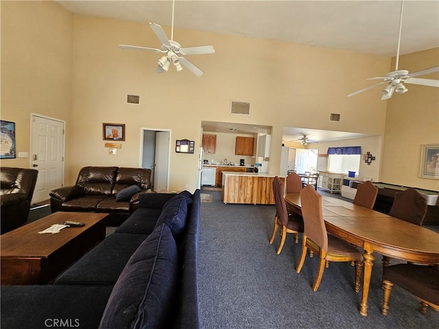 living room featuring a ceiling fan, visible vents, and dark carpet