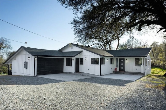 view of front of home with entry steps, an attached garage, board and batten siding, and driveway