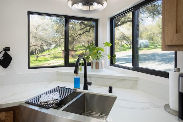 room details with a sink, brown cabinets, and light stone countertops