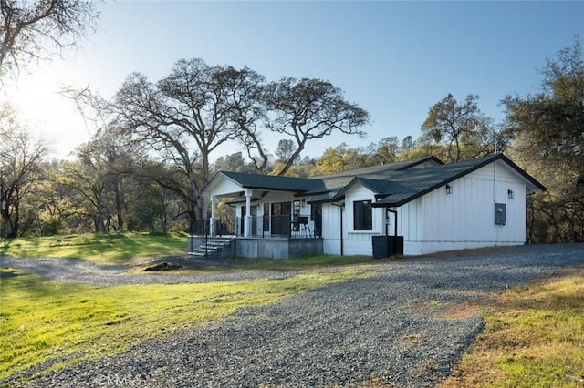 view of front of property featuring board and batten siding, a front lawn, covered porch, and driveway