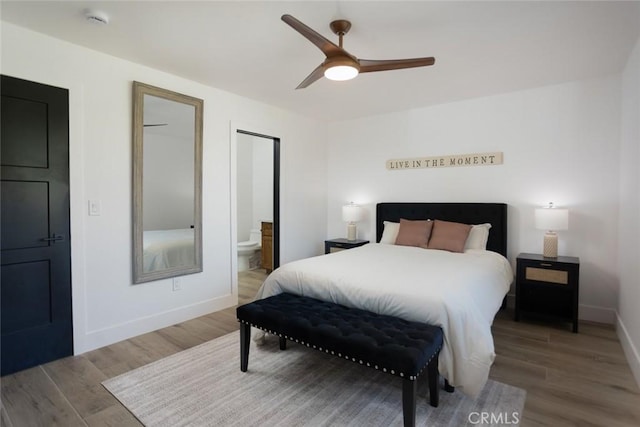 bedroom with a ceiling fan, ensuite bathroom, baseboards, and wood finished floors