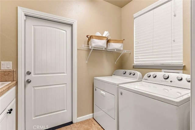 clothes washing area with washer and clothes dryer, laundry area, and light tile patterned floors