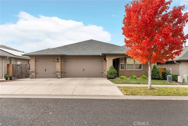 view of front of home featuring fence, stucco siding, a garage, stone siding, and driveway