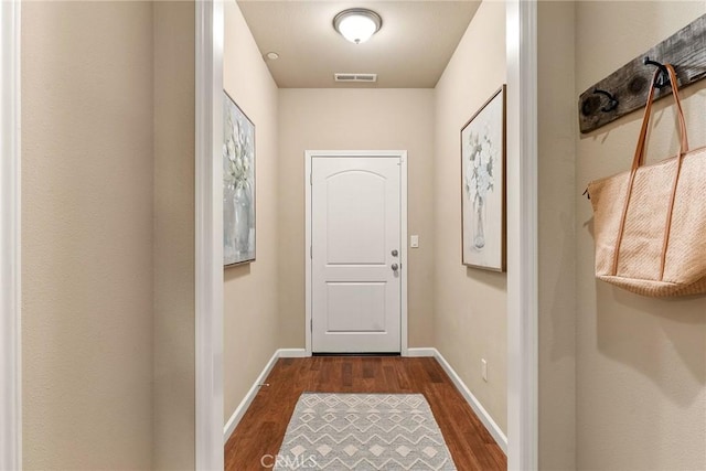 doorway with visible vents, baseboards, and dark wood-style floors