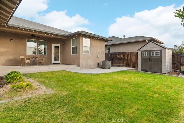 back of house featuring fence, stucco siding, a storage shed, an outdoor structure, and a patio area