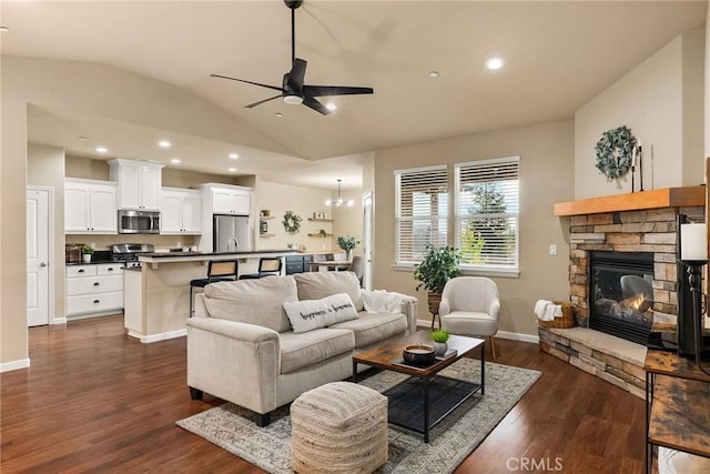 living area with dark wood-type flooring, lofted ceiling, a fireplace, baseboards, and ceiling fan