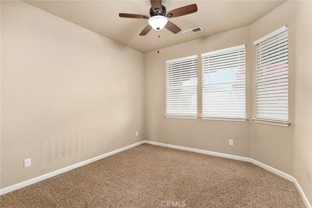 carpeted spare room featuring a ceiling fan, baseboards, and visible vents