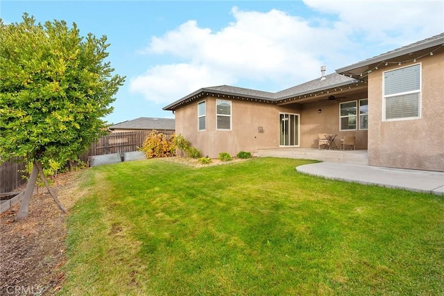 rear view of house with a patio, a yard, a fenced backyard, stucco siding, and ceiling fan