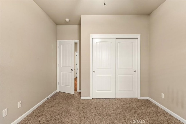 unfurnished bedroom with a closet, baseboards, and carpet floors