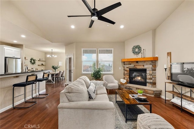 living area with recessed lighting, baseboards, dark wood-type flooring, and a stone fireplace