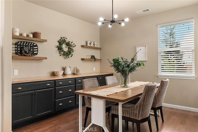 dining area featuring baseboards, visible vents, dark wood-style flooring, and a chandelier