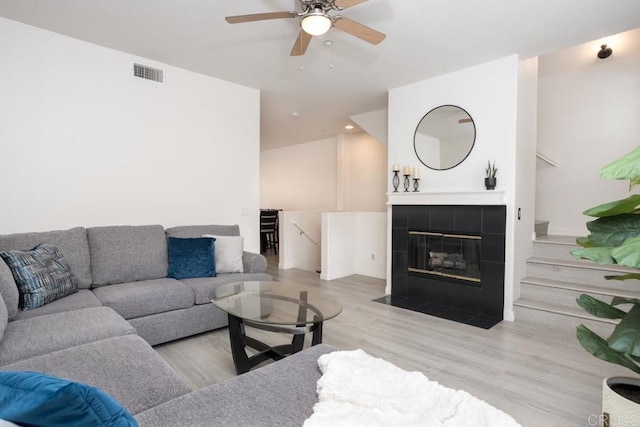 living room with a fireplace, wood finished floors, a ceiling fan, and visible vents