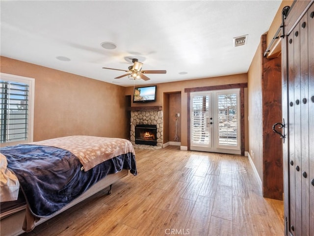 bedroom with visible vents, light wood-style flooring, baseboards, and a barn door